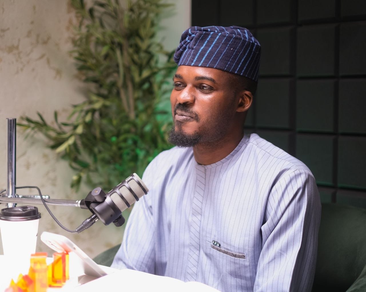 Tolu Afilaka speaking into a podcast microphone, mid-conversation.